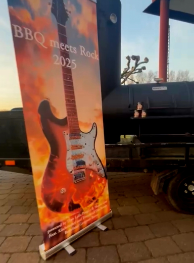 Banner mit E-Gitarre und BBQ-Eventschriftzug vor einem Grillwagen.