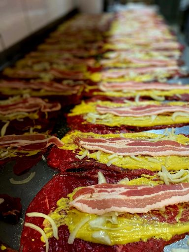 Bunte Tortillas mit Schinkenstreifen und Zwiebelstücken auf einem Backblech.